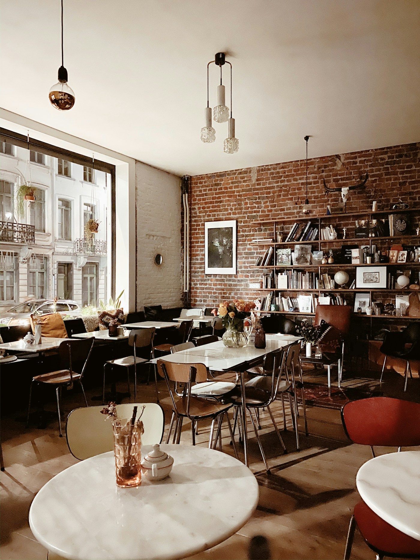 Sunlit neighborhood café with marble tables, warm wood chairs and plants